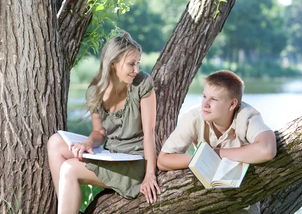 Jovem e a menina com livros na margem do lago — Fotografia de Stock