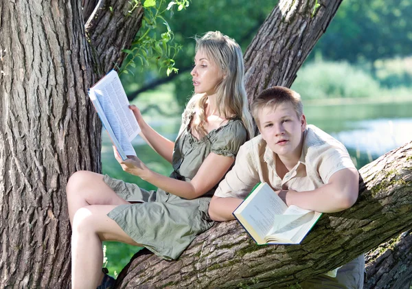 Ung kille och flickan förbereda lektioner, undersökning i vår park — Stockfoto