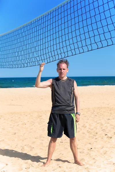 De sportieve man in de buurt van een raster voor beachvolleybal — Stockfoto