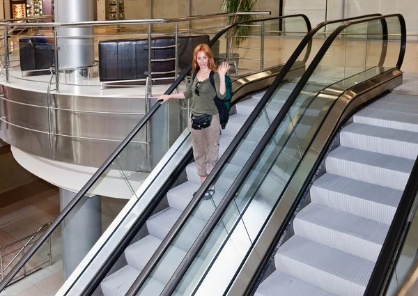 Junge Frau mit Rucksack auf der Rolltreppe — Stockfoto