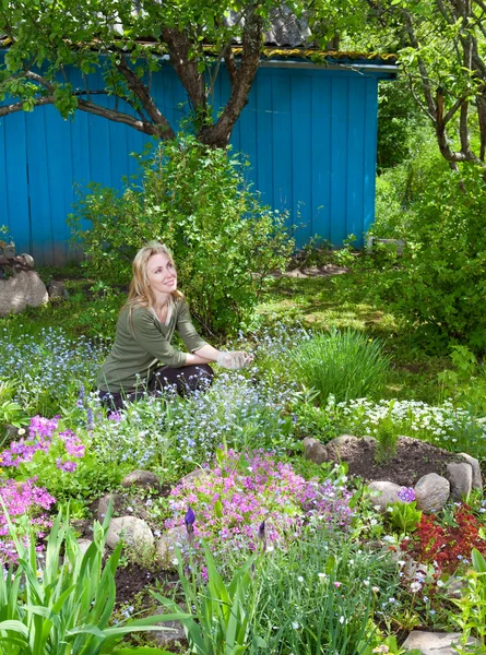 Jeune jolie femme s'occupe derrière les plantes dans le jardin — Photo