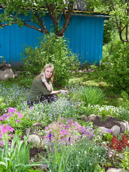 Giovane bella donna si prende cura di dietro le piante in giardino — Foto Stock