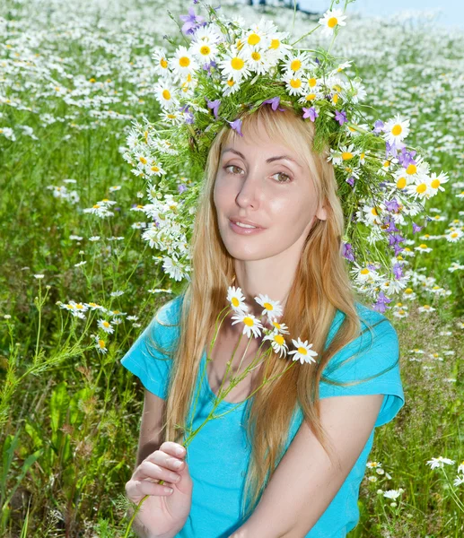Den lykkelige unge kvinnen i en krans fra ville blomster på marken – stockfoto