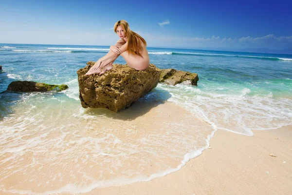 在海浪的边缘的石头上的裸体女孩. — 图库照片