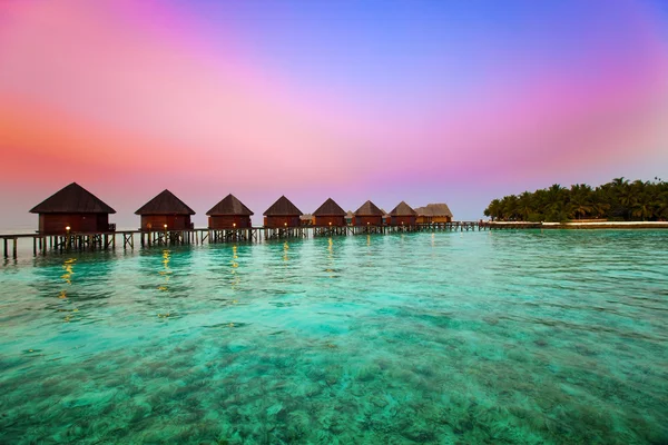Insel im Ozean, Überwasser-Villen zum Zeitpunkt des Sonnenuntergangs. — Stockfoto