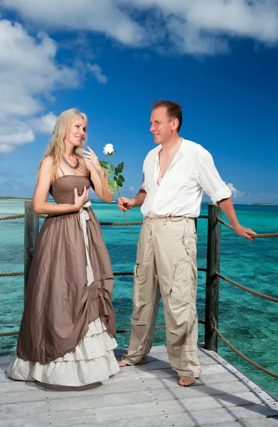 Man gives a rose to the woman on the turquoise sea background — Stock Photo, Image