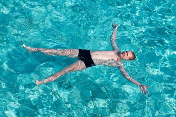Adolescente tem um resto na água transparente turquesa do oceano — Fotografia de Stock