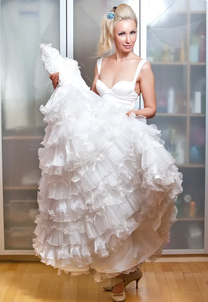 Die glückliche Braut probiert ein Hochzeitskleid an — Stockfoto
