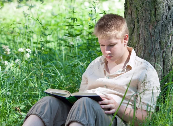 Mladý muž s knihou v parku — Stock fotografie