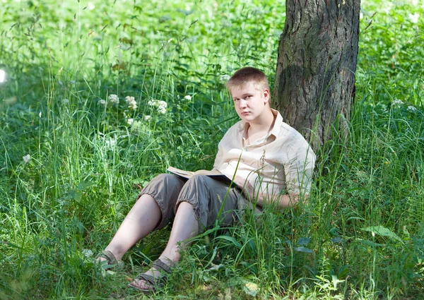 Mladý muž s knihou v parku — Stock fotografie