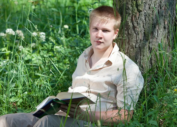 Молодой человек с книгой в парке — стоковое фото