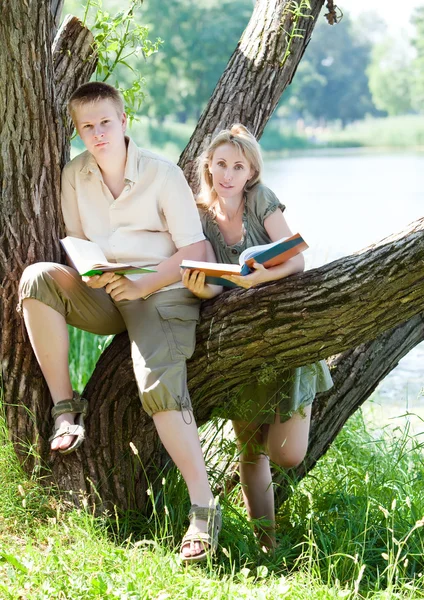 Ung kille och flickan förbereda lektioner, undersökning i vår park — Stockfoto