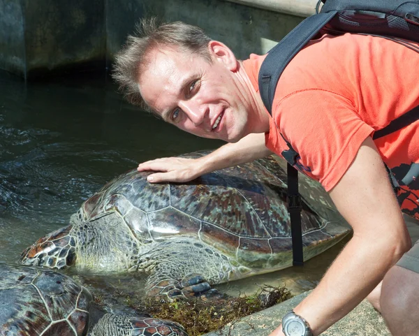 El hombre acaricia una armadura de una tortuga grande — Foto de Stock