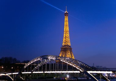 Eiffel Tower and the bridge Passerelle Debilly illuminated at night. View from the Seine quay clipart