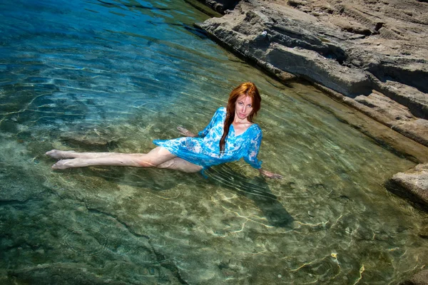De jonge mooie vrouw in een natuurlijke zee zwemmen bad onder stenen. — Stockfoto