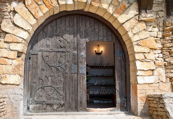 Puerta de madera semicircular con acabado metálico en una pared de piedra . —  Fotos de Stock