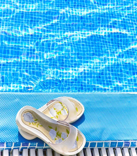 Chinelos de praia em uma borda de piscina — Fotografia de Stock