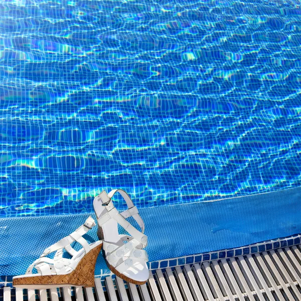Sandalias de playa en un borde de piscina — Foto de Stock