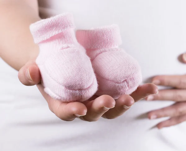Mulher grávida segurando calçado de par rosa para bebê menina — Fotografia de Stock