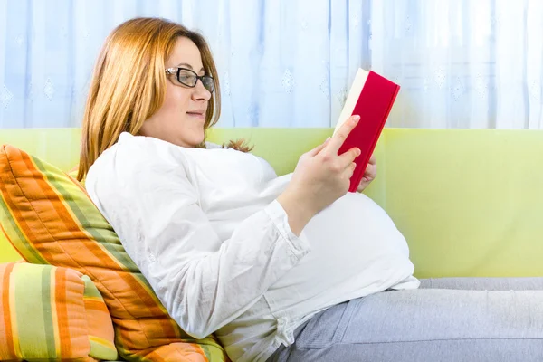 Kobieta w ciąży szczęśliwa czytając książkę — Zdjęcie stockowe
