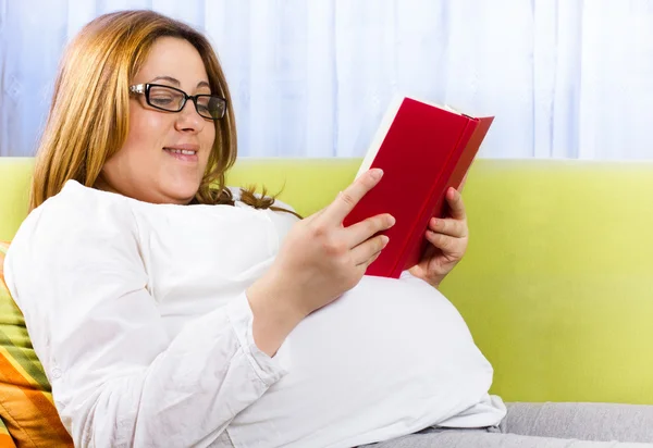 Glad gravid kvinna läser en bok — Stockfoto