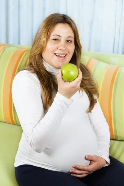Happy pregnant woman eating a green apple — Stock Photo, Image