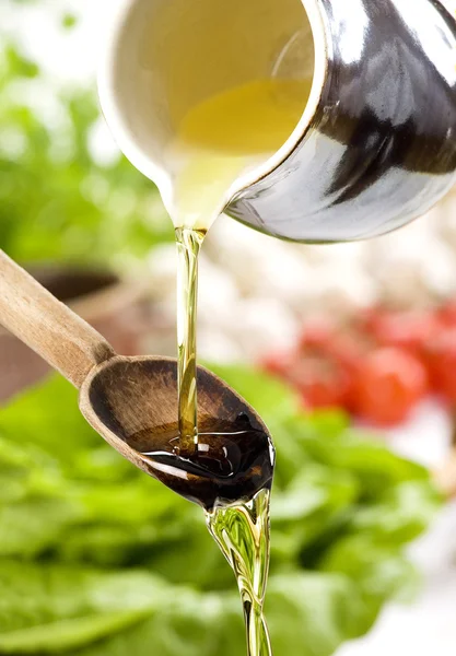 Verter aceite en la ensalada sobre una cuchara de madera — Foto de Stock