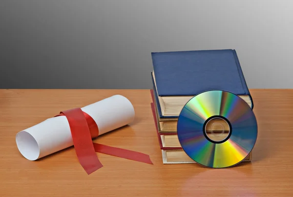 Scroll with red ribbon and books — Stock Photo, Image