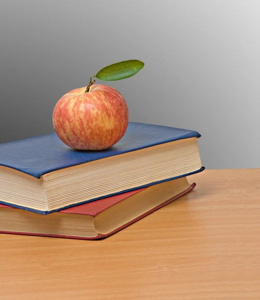Červené jablko a knihy na stole — Stock fotografie
