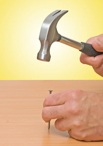 Claw hammer and hand with nail — Stock Photo, Image