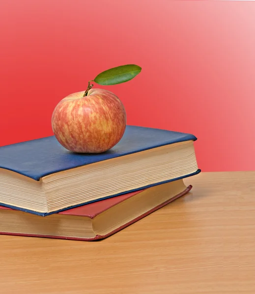 Červené jablko a knihy na stole — Stock fotografie