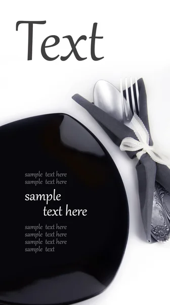 Black plate with a fork and a spoon in a napkin — Stock Photo, Image