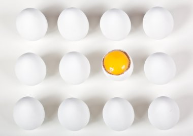 One broke egg amongst whole white eggs clipart