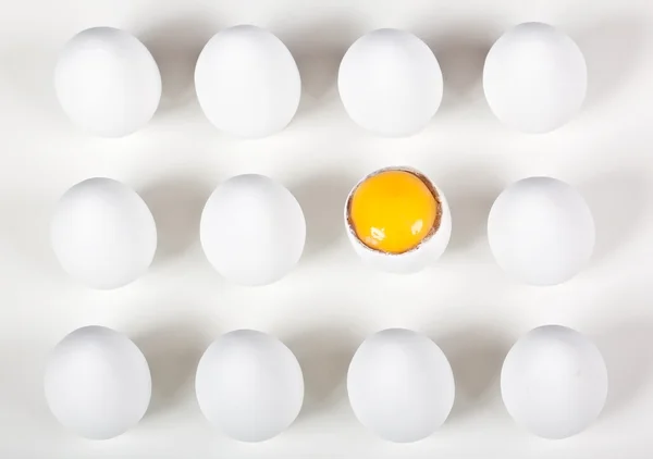 Um ovo quebrado entre ovos brancos inteiros — Fotografia de Stock