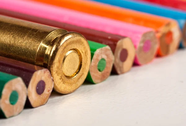 Una bala de arma junto con lápices — Foto de Stock