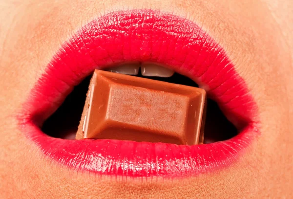 Kadın kırmızı dudaklı bir çikolata ısırmak — Stok fotoğraf