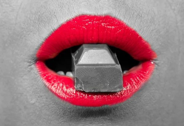 Vermelho, lábios quentes mordendo um chocolate — Fotografia de Stock