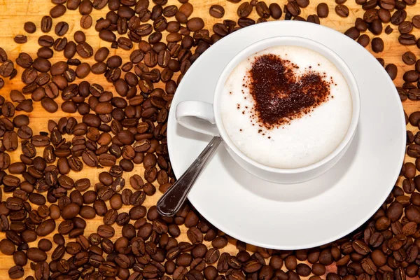 Cacao heart in white frothed coffee — Stock Photo, Image
