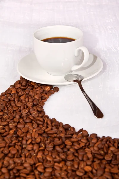 Grains de café faire un chemin vers une tasse blanche de café — Photo