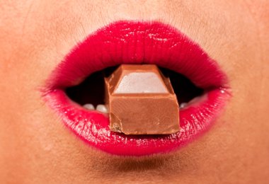 Red, hot lips biting a chocolate clipart