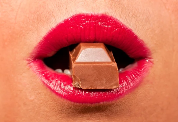 Red, hot lips biting a chocolate — Stock Photo, Image