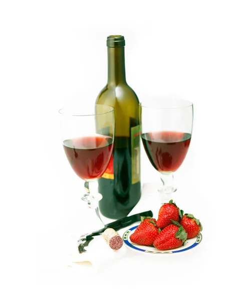 Láhev červeného vína a dvě sklenice s jahodami — Stock fotografie