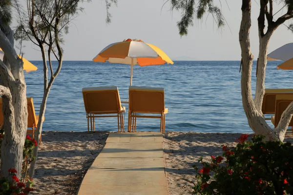 Zwei Liegestühle und Sonnenschirm am Strand. tigaki, griechenland — Stockfoto