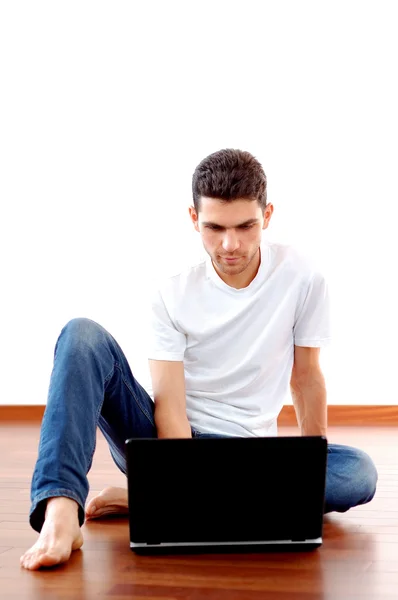 Νεαρός άνδρας που κάθονται με τον φορητό υπολογιστή στο σπίτι — Φωτογραφία Αρχείου