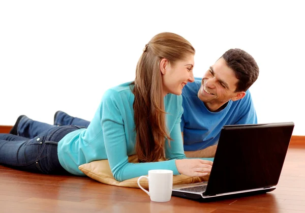 Χαμογελώντας νεαρό ζευγάρι χρησιμοποιώντας φορητό υπολογιστή στο σπίτι — Φωτογραφία Αρχείου