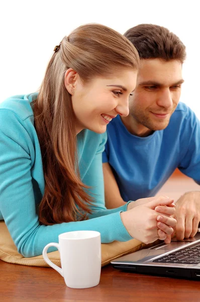 Smiling young couple using laptop at home — Stock Photo, Image