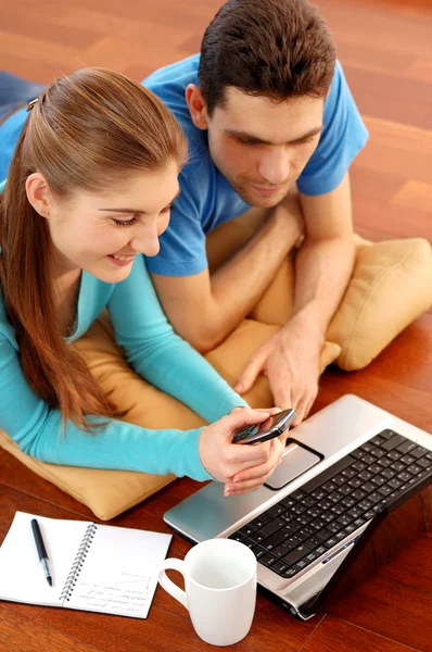 Χαμογελώντας νεαρό ζευγάρι χρησιμοποιώντας φορητό υπολογιστή στο σπίτι — Φωτογραφία Αρχείου