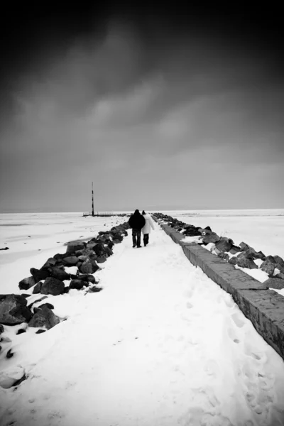 Couple walking snowy pier — Stock Photo, Image
