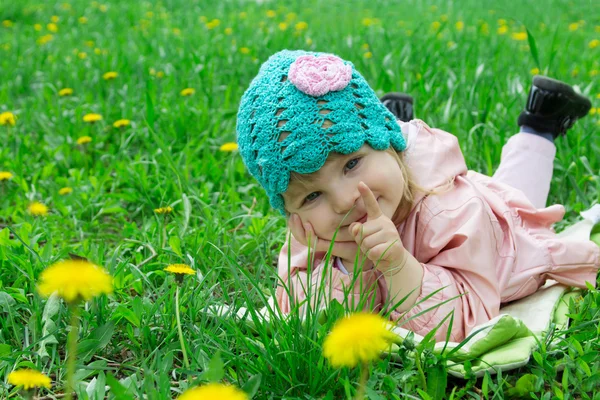 Baby girl lying among field of dandelions — Stock Photo, Image