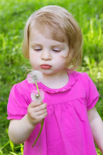 Baby girl blowing dandelion — Stock Photo, Image